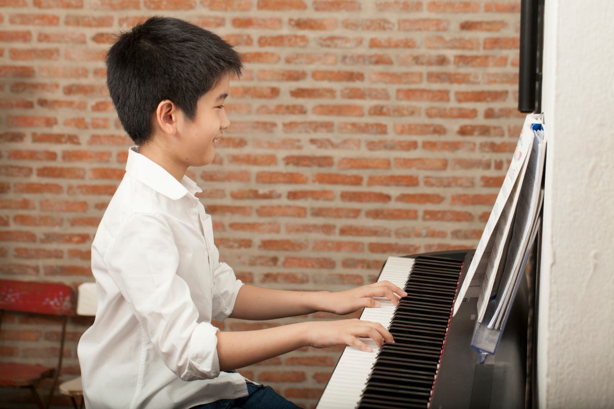 male child playing the Piano and smiling